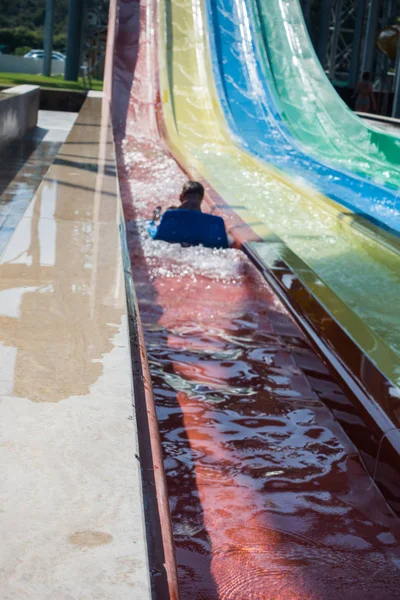 O menino monta um slide no parque aquático — Fotografia de Stock