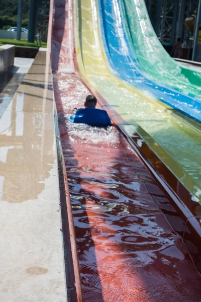 O menino monta um slide no parque aquático — Fotografia de Stock