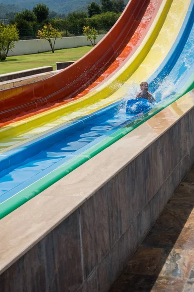 O menino monta um slide no parque aquático — Fotografia de Stock