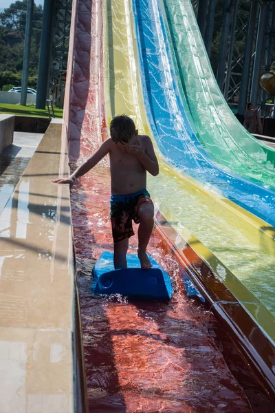 O menino monta um slide no parque aquático — Fotografia de Stock