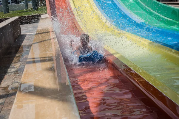 O menino monta um slide no parque aquático — Fotografia de Stock