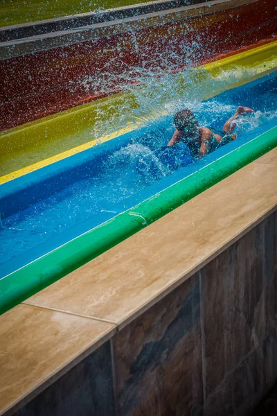 O menino monta um slide no parque aquático — Fotografia de Stock