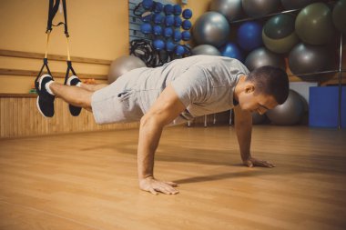 Genç adam bir spor salonunda trx devreye girer