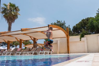 Çocuk havuza atlıyor.