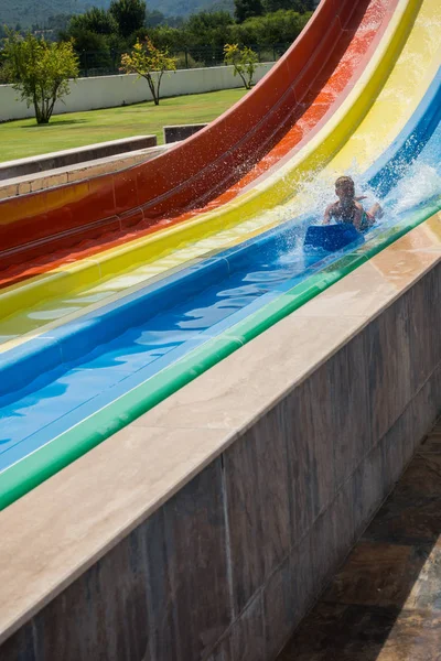 O menino monta um slide no parque aquático — Fotografia de Stock