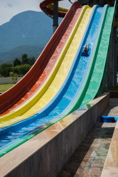 O menino monta um slide no parque aquático — Fotografia de Stock