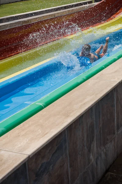 The boy rides a slide in the water park — Stock Photo, Image