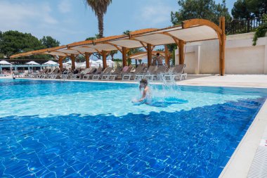 Çocuk havuza atlıyor.