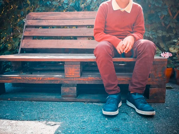 Stylish boy sits on a wooden bench — Stock Photo, Image