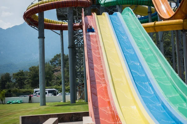 O menino monta um slide no parque aquático — Fotografia de Stock