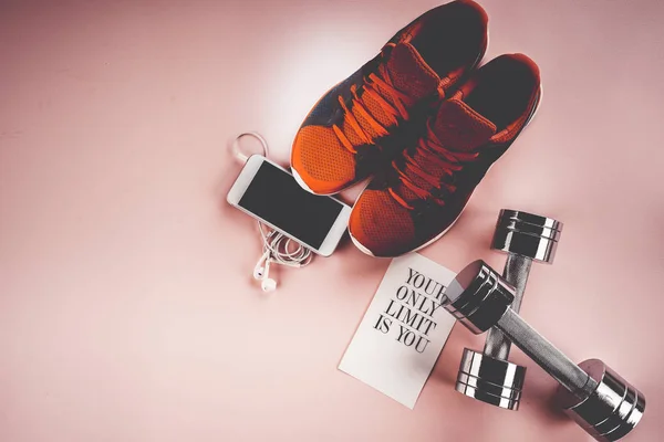 Zapatillas de deporte, teléfono y mancuernas sobre un fondo rosa — Foto de Stock