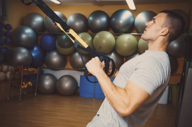Genç adam bir spor salonunda trx devreye girer