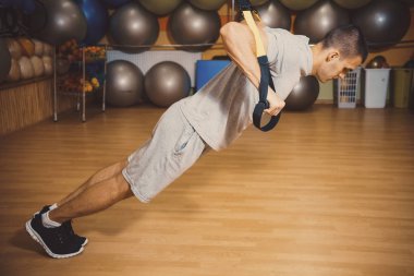 Genç adam bir spor salonunda trx devreye girer