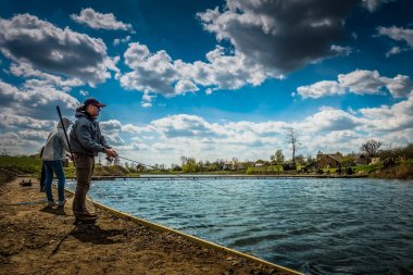 Vinnytsia, Ukraine - CIRCA 2018: Group of friends fishing by lake. clipart