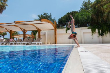 Çocuk havuza atlıyor.