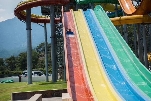 O menino monta um slide no parque aquático — Fotografia de Stock