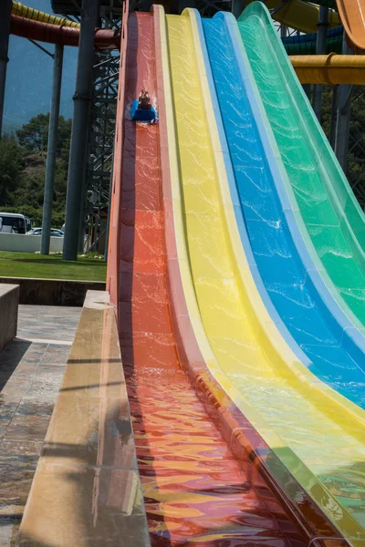 O menino monta um slide no parque aquático — Fotografia de Stock