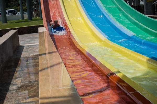 O menino monta um slide no parque aquático — Fotografia de Stock