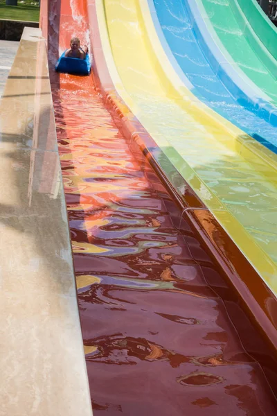 O menino monta um slide no parque aquático — Fotografia de Stock