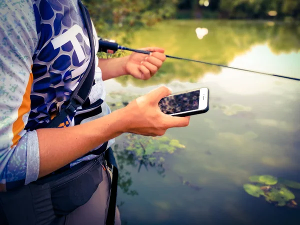 漁師は電話で夏に湖で釣りをしています — ストック写真