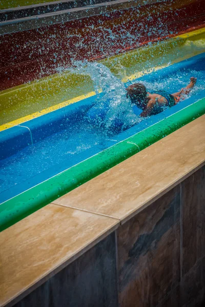 The boy rides a slide in the water park — Stock Photo, Image