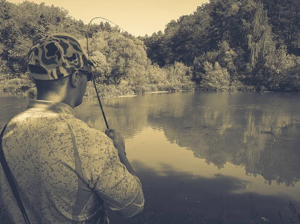 O pescador está pescando no lago no verão — Fotografia de Stock