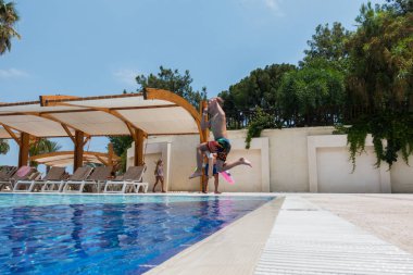 Çocuk havuza atlıyor.