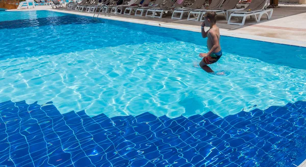 A fiú a medencébe ugrik. — Stock Fotó