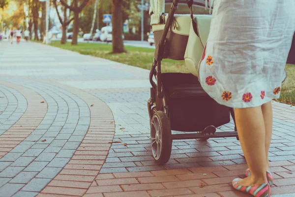 Madre con un cochecito en un paseo — Foto de Stock