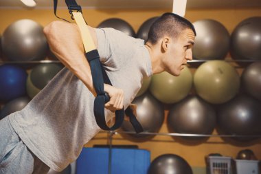 Genç adam bir spor salonunda trx devreye girer