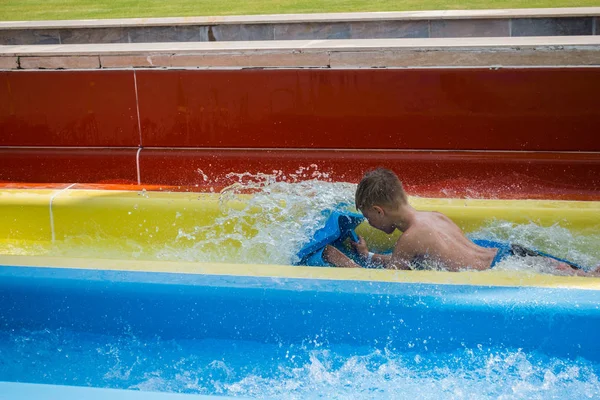 El chico monta un tobogán en el parque acuático —  Fotos de Stock