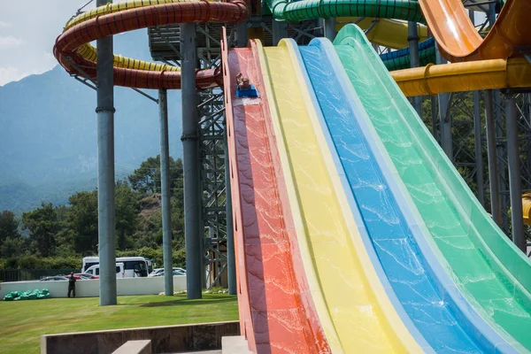 O menino monta um slide no parque aquático — Fotografia de Stock