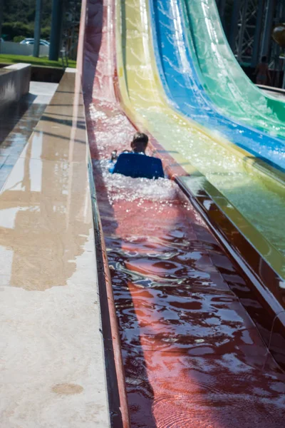 Chłopiec jeździ do slajdu w parku wodnego — Zdjęcie stockowe