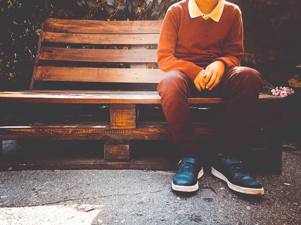 Stylish boy sits on a wooden bench — Stock Photo, Image
