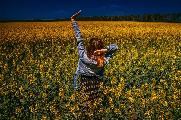 Een meisje in een veld met koolzaad — Stockfoto