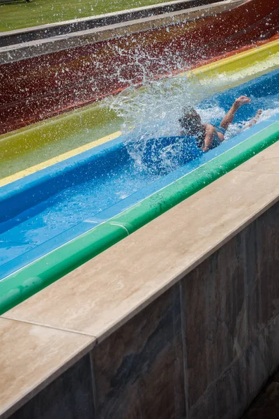 O menino monta um slide no parque aquático — Fotografia de Stock