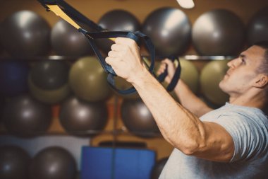 Genç adam bir spor salonunda trx devreye girer