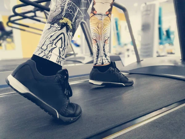 feet in sneakers on a treadmill