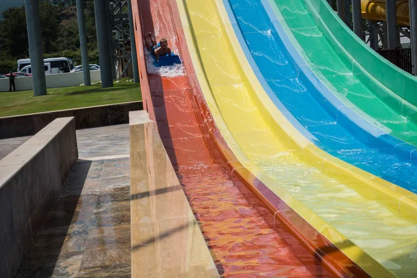 O menino monta um slide no parque aquático — Fotografia de Stock