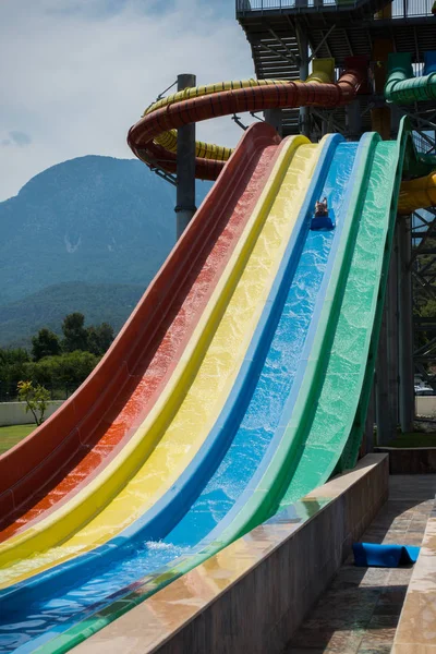 O menino monta um slide no parque aquático — Fotografia de Stock