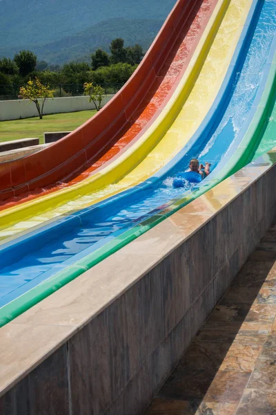 O menino monta um slide no parque aquático — Fotografia de Stock