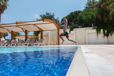 Çocuk havuza atlıyor.