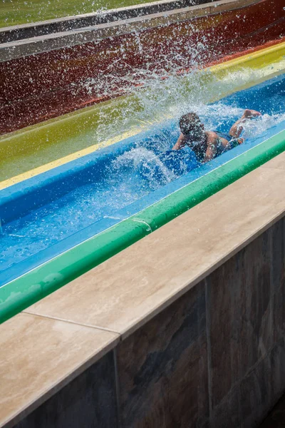 O menino monta um slide no parque aquático — Fotografia de Stock