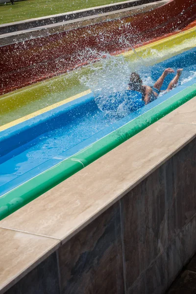 O menino monta um slide no parque aquático — Fotografia de Stock