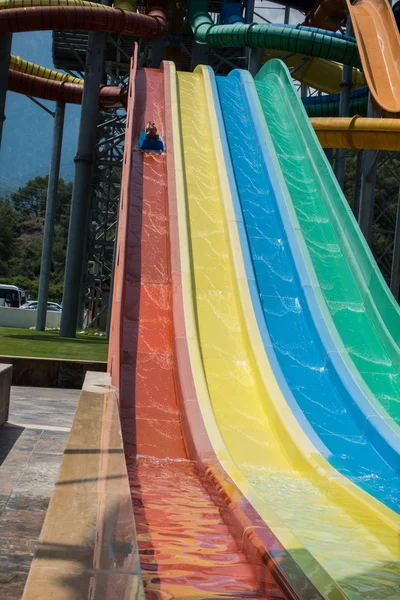 O menino monta um slide no parque aquático — Fotografia de Stock