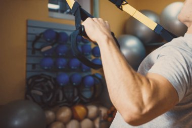 Genç adam bir spor salonunda trx devreye girer