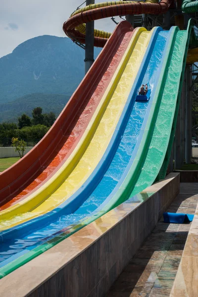 O menino monta um slide no parque aquático — Fotografia de Stock