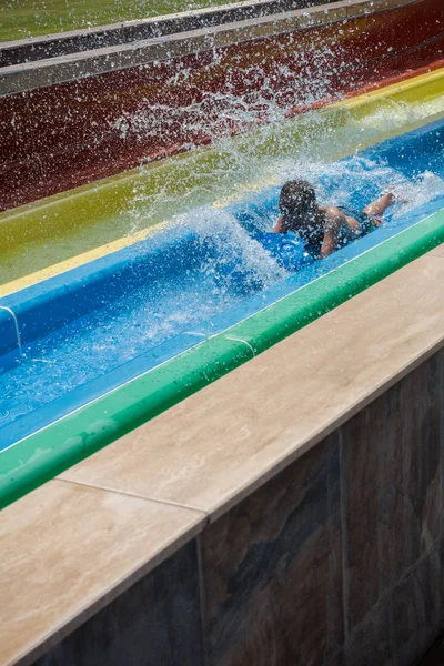 O menino monta um slide no parque aquático — Fotografia de Stock