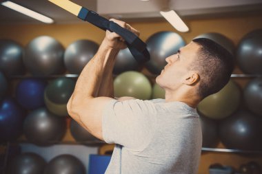 Genç adam bir spor salonunda trx devreye girer