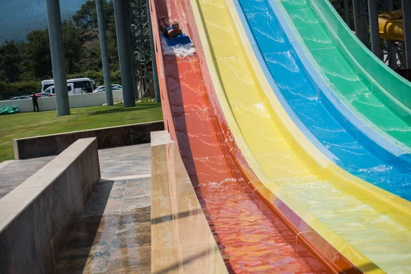 O menino monta um slide no parque aquático — Fotografia de Stock